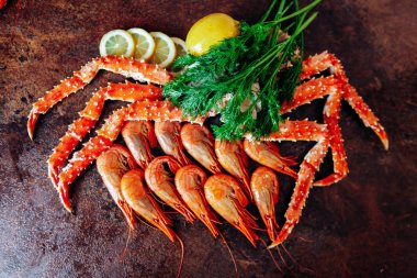 Masanın üzerinde karides, yengeç, limon ve bitkiler var. Kırmızımsı renk tablosu.