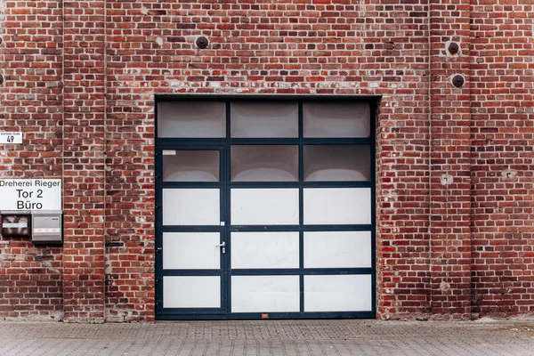 Porta de garagem grande com parede de tijolo e calçada de asfalto — Fotografia de Stock