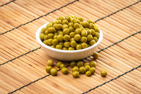 Guisantes verdes enlatados en el tazón sobre fondo de madera —  Fotos de Stock