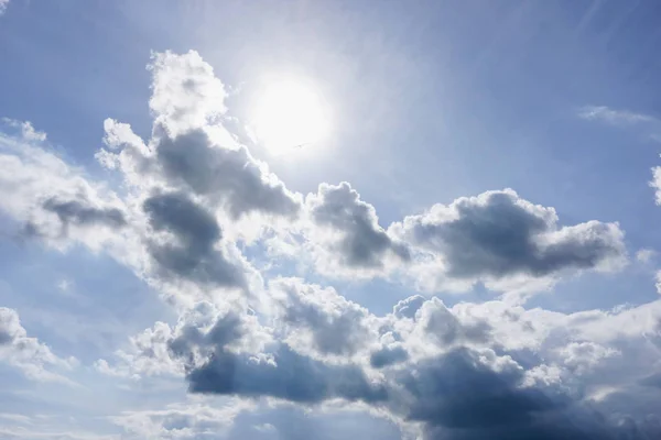 Blue sky with clouds and sun. Beautiful photo of the sun with clouds. The sun behind the clouds. — Stock Photo, Image