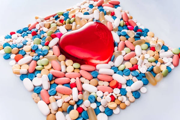 Pilules de médecine pharmaceutique assorties, comprimé et figurine sous la forme d'un cœur. Pilules fond. tas de divers comprimés de médecine assortis et des pilules de différentes couleurs sur fond blanc. Santé — Photo
