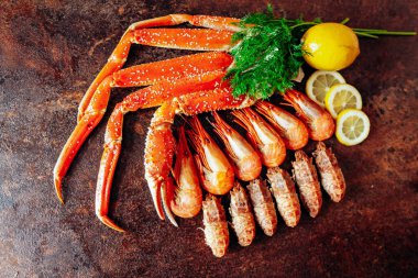 Kırmızı arka planda yengeç, karides, bitki ve limon kompozisyonu