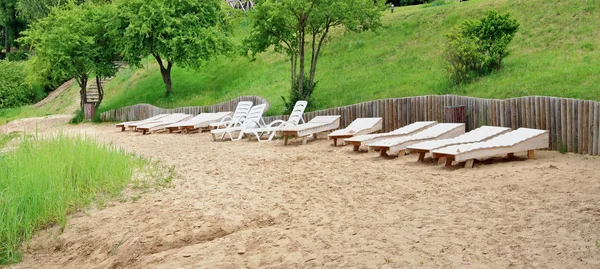 Fragment av den offentliga sandstranden med vit trä chaise loun — Stockfoto