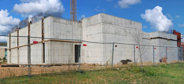 Atrás da cerca de malha de ferro é uma caixa de concreto de um recém-construído — Fotografia de Stock