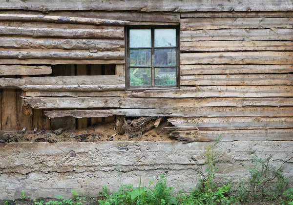 A parede de madeira podre de um celeiro de aldeia com uma janela — Fotografia de Stock