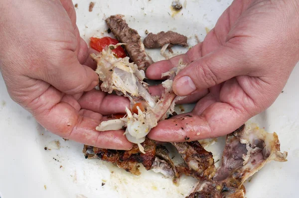 Kobiecych rąk kopać w kości i odpady z grilla kurczak — Zdjęcie stockowe