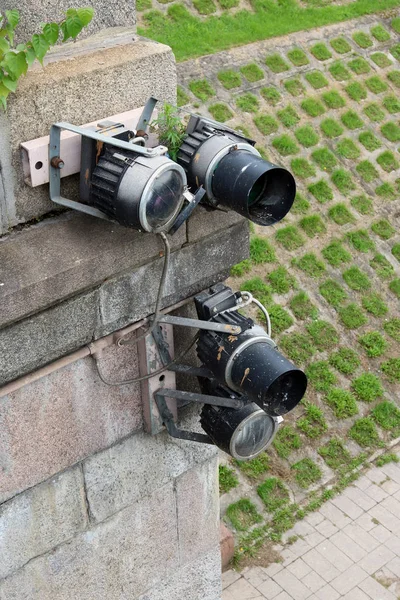 Old dirty floodlights hang on the granite pillar of the city bri — Stock Photo, Image