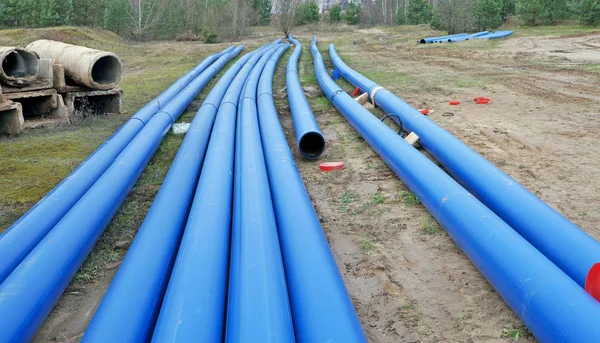 Довгі сині пластикові каналізаційні труби в дерев'яному промисловому ландшафті — стокове фото