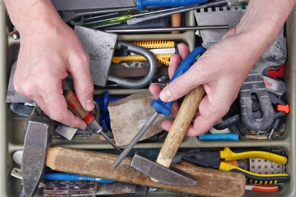 Старий дід будинку ремонтант оглядає іржаві інструменти — стокове фото