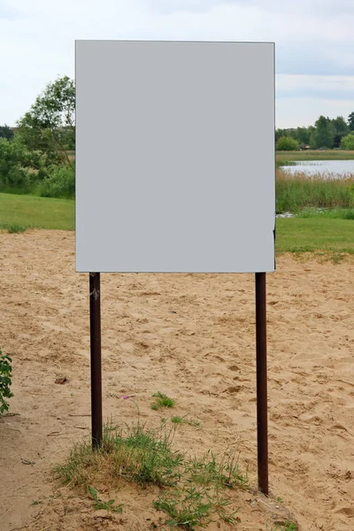 An empty information board is installed on a sandy beach near th — Stock Photo, Image