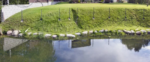 Na margem de uma lagoa aldeia cresce grama e mentira pedra de granito — Fotografia de Stock