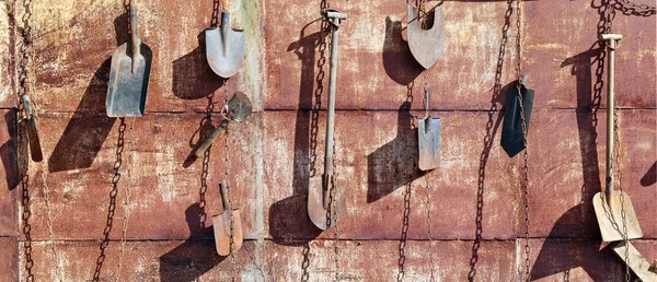 On the rusty metal wall of the village barn hang on the chains u — Stock Photo, Image