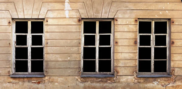 Tre finestre bianche di legno nella parete intonacata gialla di un — Foto Stock