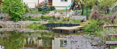 Küçük kırsal gölet ve köy yakınlarındaki çimenler kırsal ev manzarası