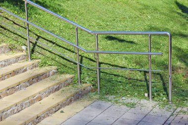 Parlak paslanmaz çelik parmaklıkları olan bir merdiven parçası.
