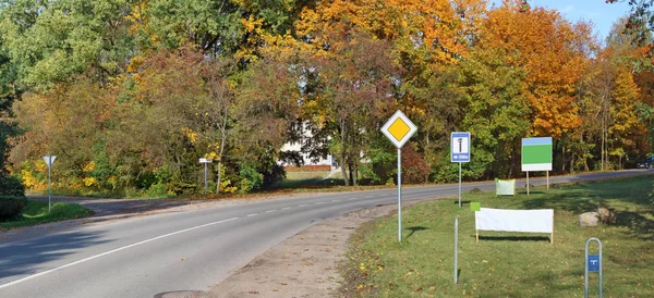 En la curva de la carretera rural, señales de tráfico y pancarta publicitaria —  Fotos de Stock