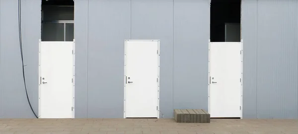 Drie nieuwe witte gepantserde deuren in de stalen muur van een stedelijke unfi — Stockfoto