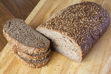 Ahşap bir masa üstünde susam taneleri ile ekmek