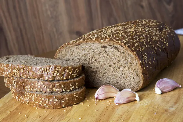 Ahşap bir masa üstünde susam taneleri ile ekmek