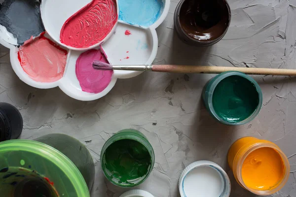 Gri desen arkaplanına farklı renkler çizmek için Gouache. Gouache kutuları rastgele yerleştirilmiş. Arkaplan gri desen fırça darbeleri