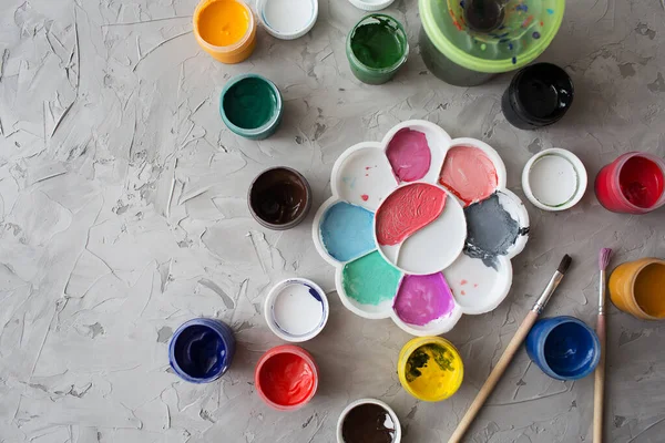 Gri desen arkaplanına farklı renkler çizmek için Gouache. Gouache kutuları rastgele yerleştirilmiş. Arkaplan gri desen fırça darbeleri