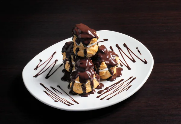 French profiterole with chocolate icing on a plate — Stock Photo, Image