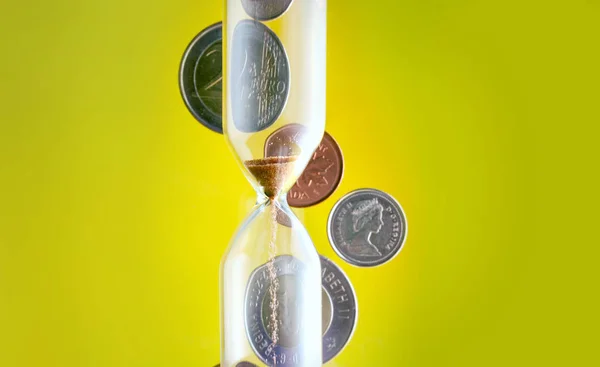 Hourglass with coins in the background Rechtenvrije Stockfoto's