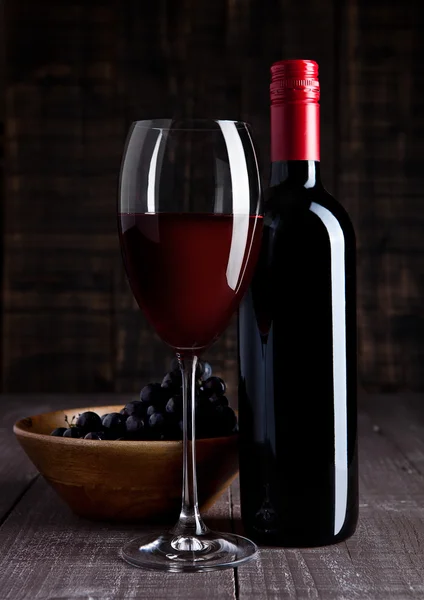 Μπουκάλι και ποτήρι κόκκινο κρασί με τα σταφύλια σε μπολ — Φωτογραφία Αρχείου