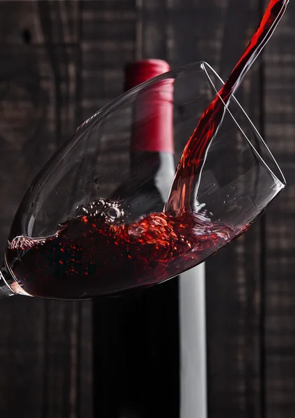 Pouring red wine into the glass from bottle — Stock Photo, Image