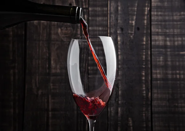 Pouring red wine into the glass from bottle — Stock Photo, Image