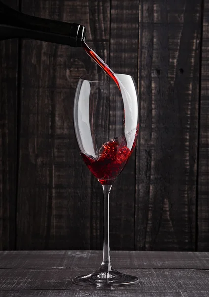 Pouring red wine into the glass from bottle — Stock Photo, Image