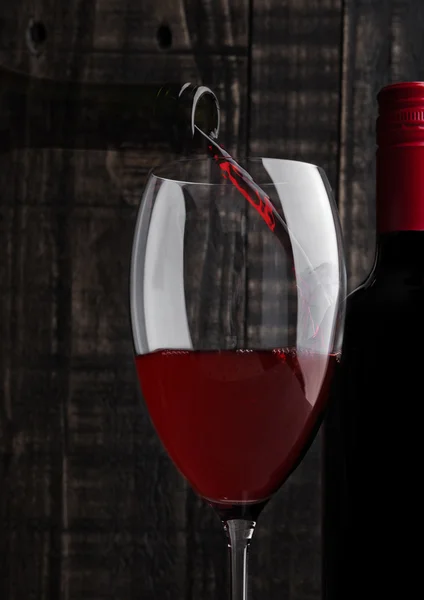 Pouring red wine into the glass from bottle — Stock Photo, Image