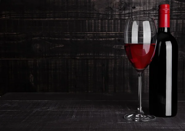 Botella y copa de vino tinto sobre fondo de madera — Foto de Stock