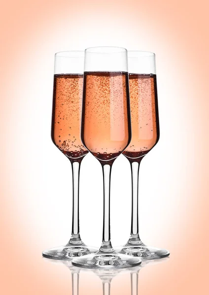 Glass of pink rose champagne with bubbles on pink