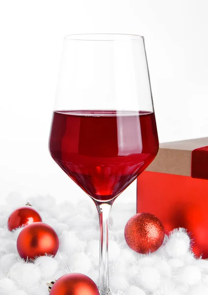 Glass of red wine on snow with christmas balls — Stock Photo, Image