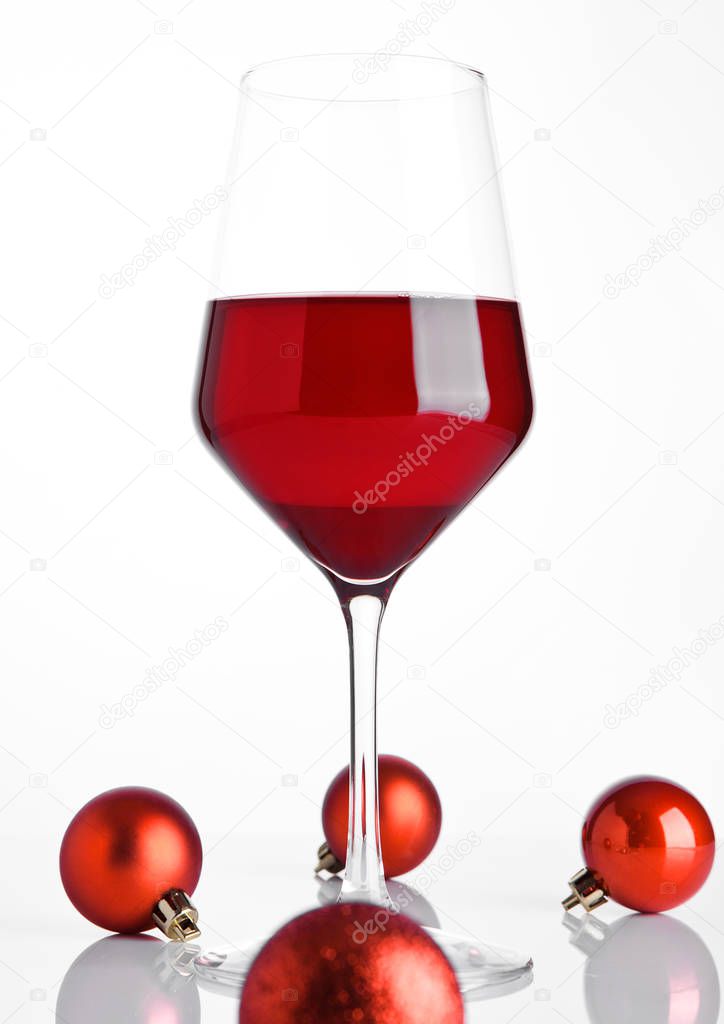 Glass of red wine on snow with christmas balls
