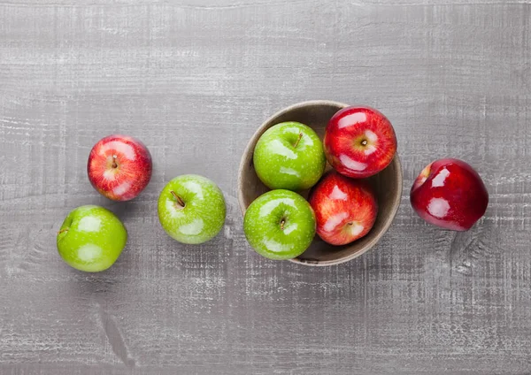 Red and green apples in wooden bowl on board — Stock Photo, Image