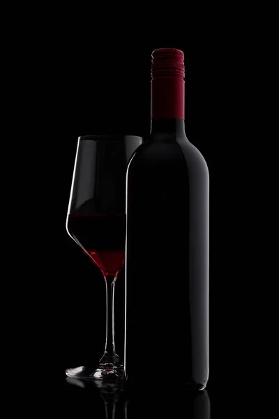 Copa de vino tinto con botella de cerca en negro — Foto de Stock