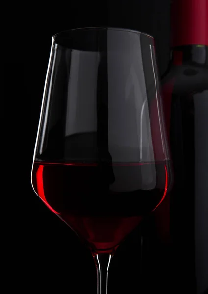 Glas Rotwein mit Flasche in Nahaufnahme auf schwarz — Stockfoto