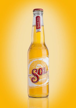 LONDON, UK - DECEMBER 15, 2016: Bottle of Sol Mexican Beer on yellow background. From the Cuauhtemoc Moctezuma Brewery, in Monterey, Mexico, it was first introduced in the 1890's as El Sol. clipart