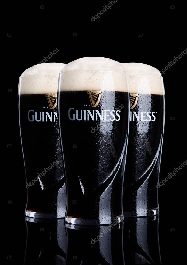 LONDON, UK - FEBRUARY 26, 2017: Glasses of Guinness original beer on black background. Guinness beer has been produced since 1759 in Dublin, Ireland.