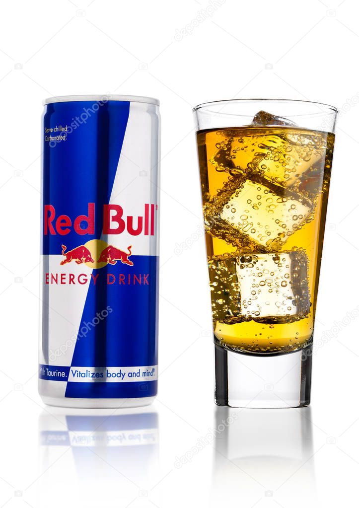 LONDON, UK - APRIL 12, 2017: Can of Red Bull Energy Drink with glass and ice cubes on white background with reflection. Red Bull is the most popular energy drink in the world.