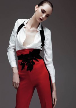 Kırmızı pantolon ve beyaz gömlek giymiş bir modeldir