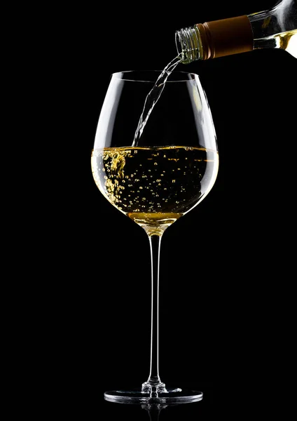 Pouring white wine from bottle to glass on black — Stock Photo, Image