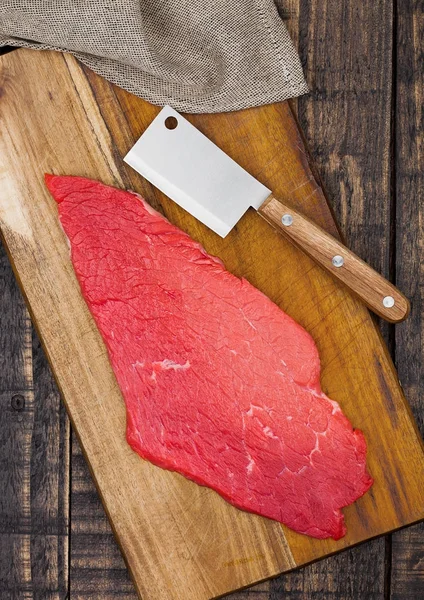 Čerstvé syrové hovězí steak v černém na dřevěné desce — Stock fotografie