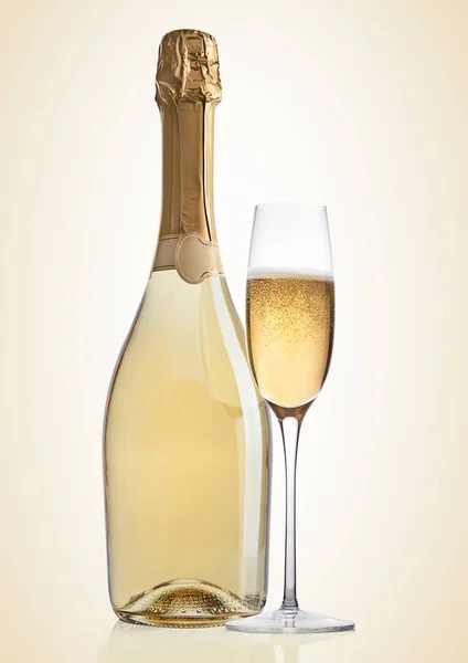 Bottle and glass of yellow champagne on yellow — Stock Photo, Image