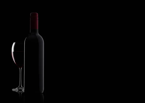 Glass of red wine with bottle with shape on black — Stock Photo, Image