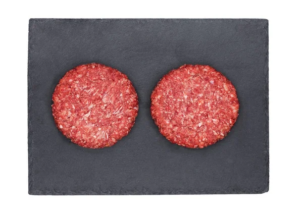 Сырые бургеры из говядины на каменной тарелке — стоковое фото
