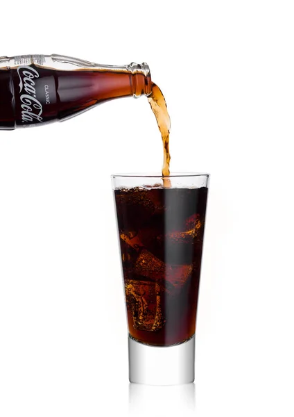 London, Storbritannien - 02 januari 2018: Häller Coca Cola läsk drink från flaska till glas på vitt. Drycken produceras och tillverkas av The Coca-Cola Company. — Stockfoto