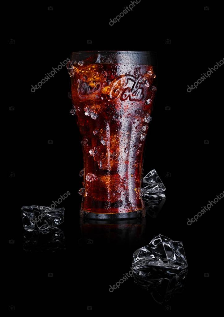 LONDON, UK - JANUARY 02, 2018: Original glass of Coca Cola drink with ice and dew on black background. The drink is produced and manufactured by The Coca-Cola Company.